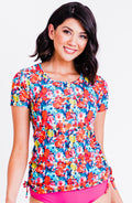 Woman wearing a colorful floral top with a plain background
