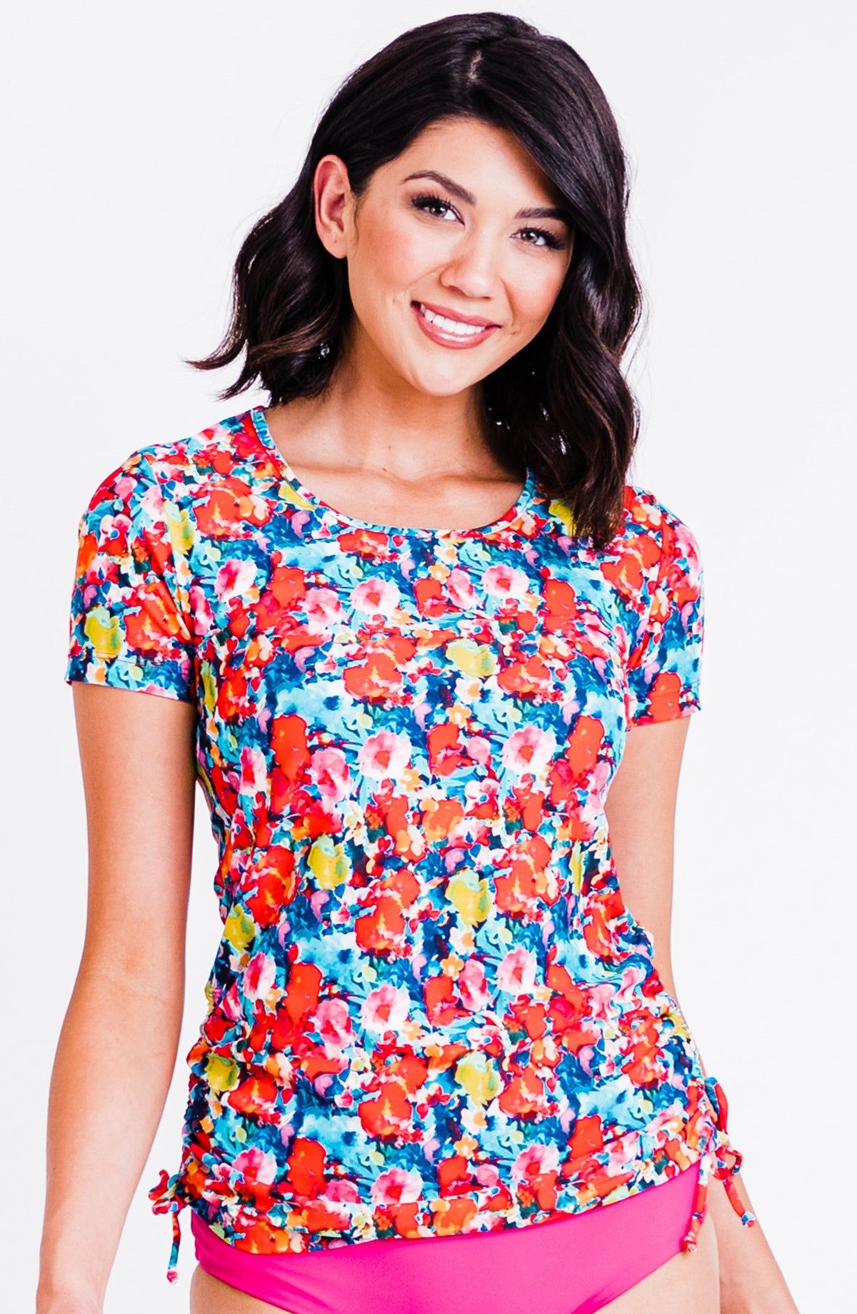 Woman wearing a colorful floral top with a plain background