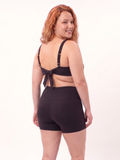 Sienna Swim Bra | Plus Size in black shown from the back on a smiling model with adjustable straps and bow detail. Supportive comfortable size-inclusive swimwear for every body