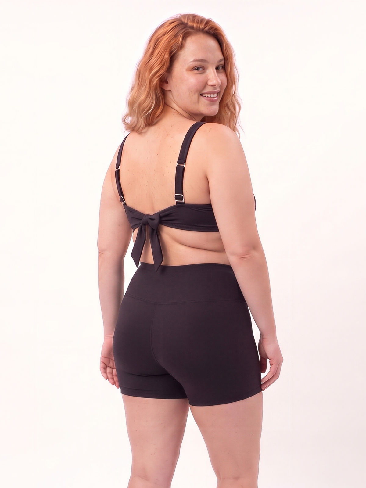 Sienna Swim Bra | Plus Size in black shown from the back on a smiling model with adjustable straps and bow detail. Supportive comfortable size-inclusive swimwear for every body