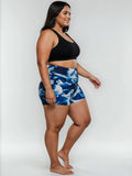 Swim Shorts | Plus Size shown on a smiling woman in blue patterned high waisted swim shorts and a black swim top for a comfortable flattering fit.