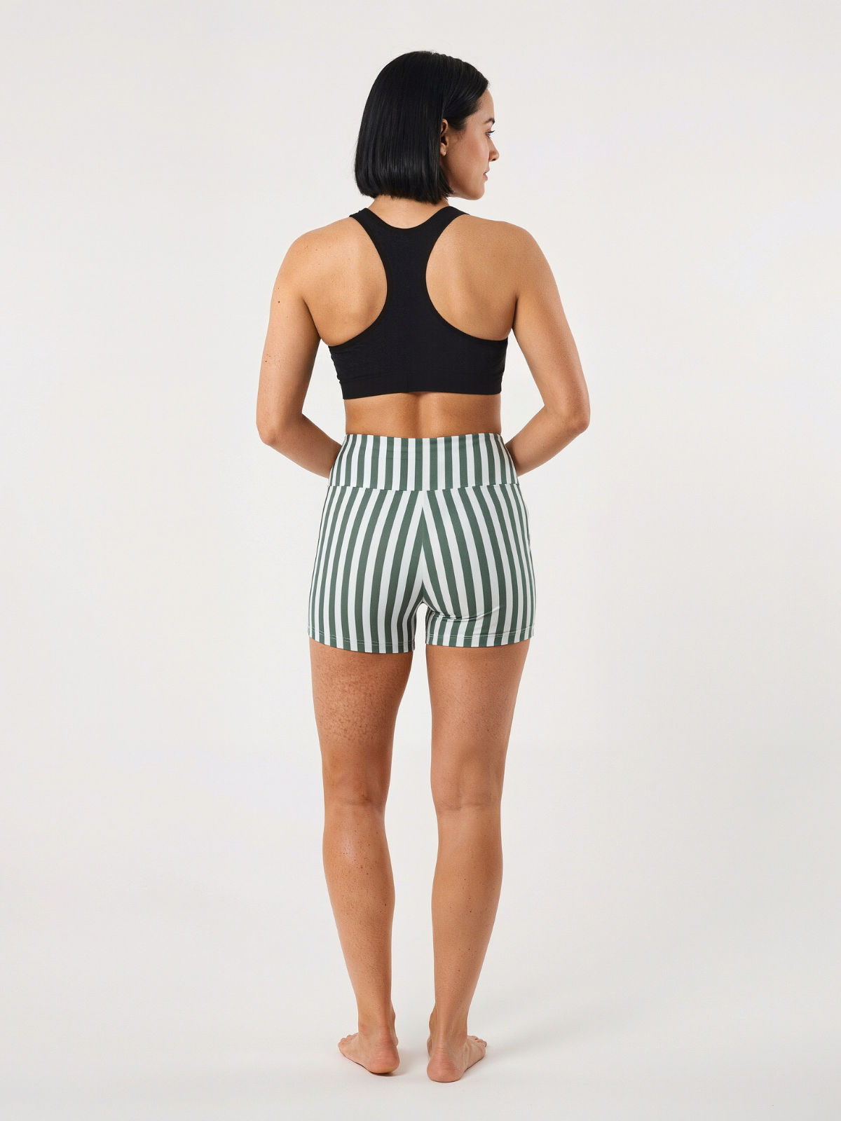Swim Shorts with green and white vertical stripes shown from the back on a woman wearing a black swim top with a comfortable fit