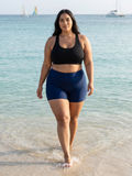 Swim Shorts | Plus Size shown on a woman walking through shallow ocean water in navy swim shorts and a black top. Size-inclusive modest swimwear for every body
