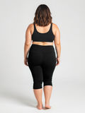 Woman seen from behind wearing black Capri Swim Leggings | Plus Size paired with a supportive black swim top, showcasing size-inclusive, modest swimwear designed for a comfortable fit. Swimwear designed for every body.