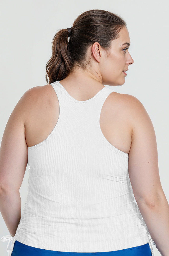 Woman wearing a white tank top against a plain background