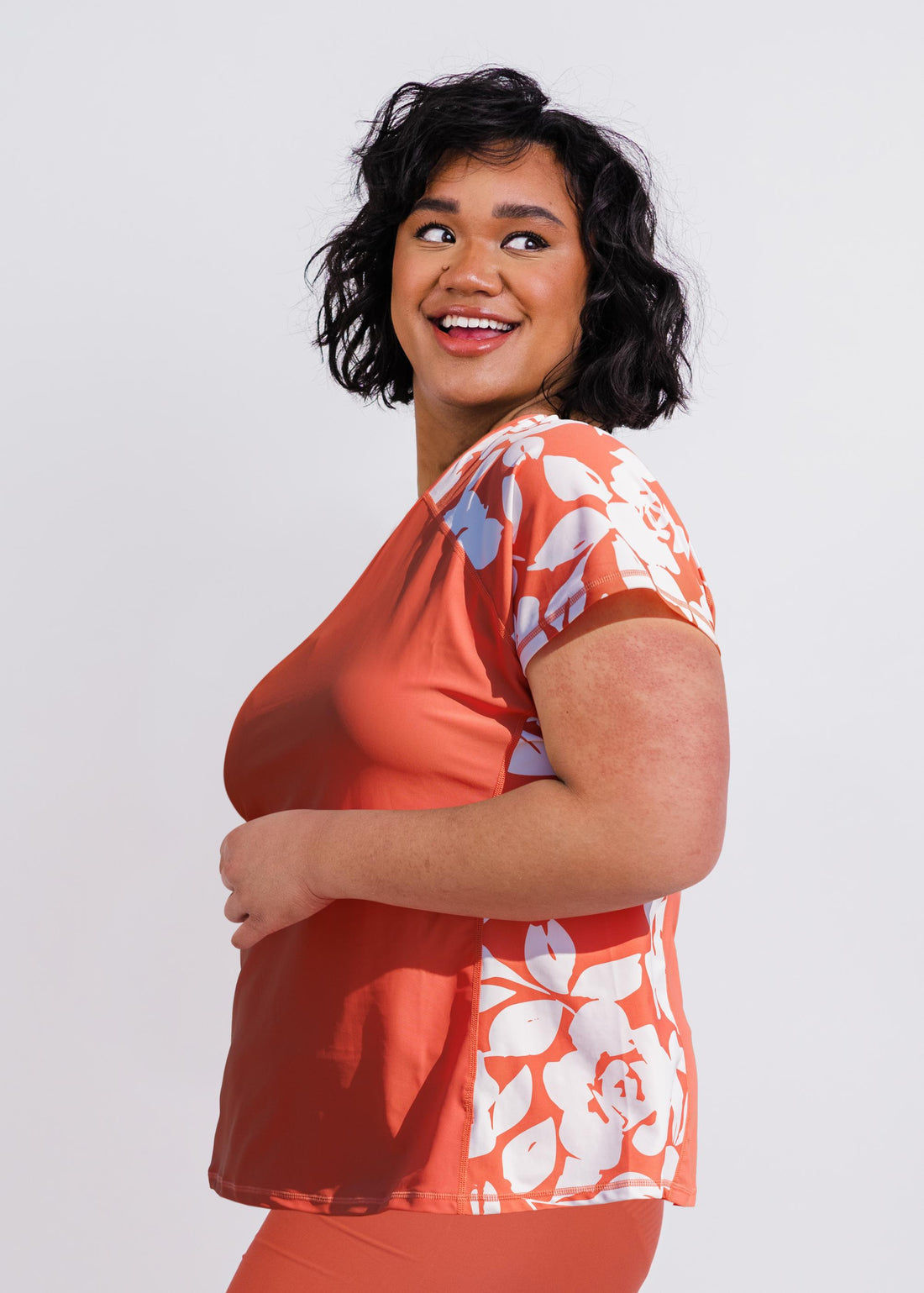 Loose Fit Adele Swim Top | Plus Size worn by a woman on a sunny beach with striped sleeves and a relaxed fit. Supportive size-inclusive swimwear for every body.