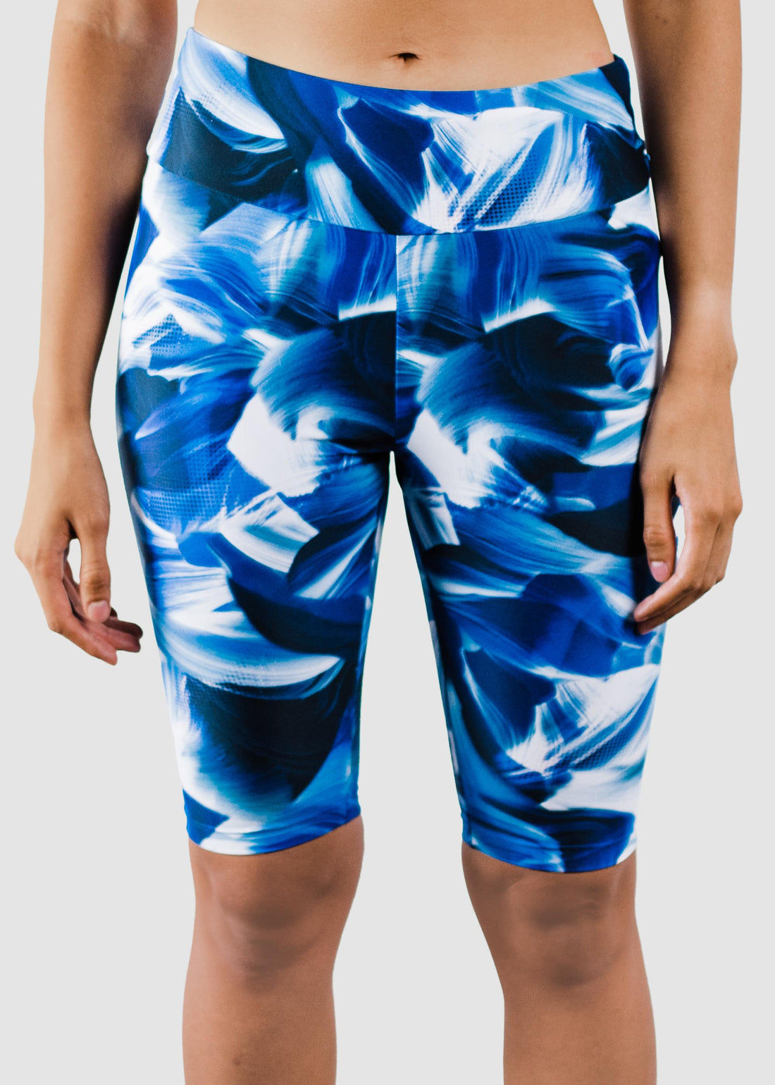 Woman wearing navy Long Bike Swim Shorts and matching swim top standing on the beach with a relaxed, confident pose, showcasing size-inclusive, modest, supportive swimwear designed for every body.