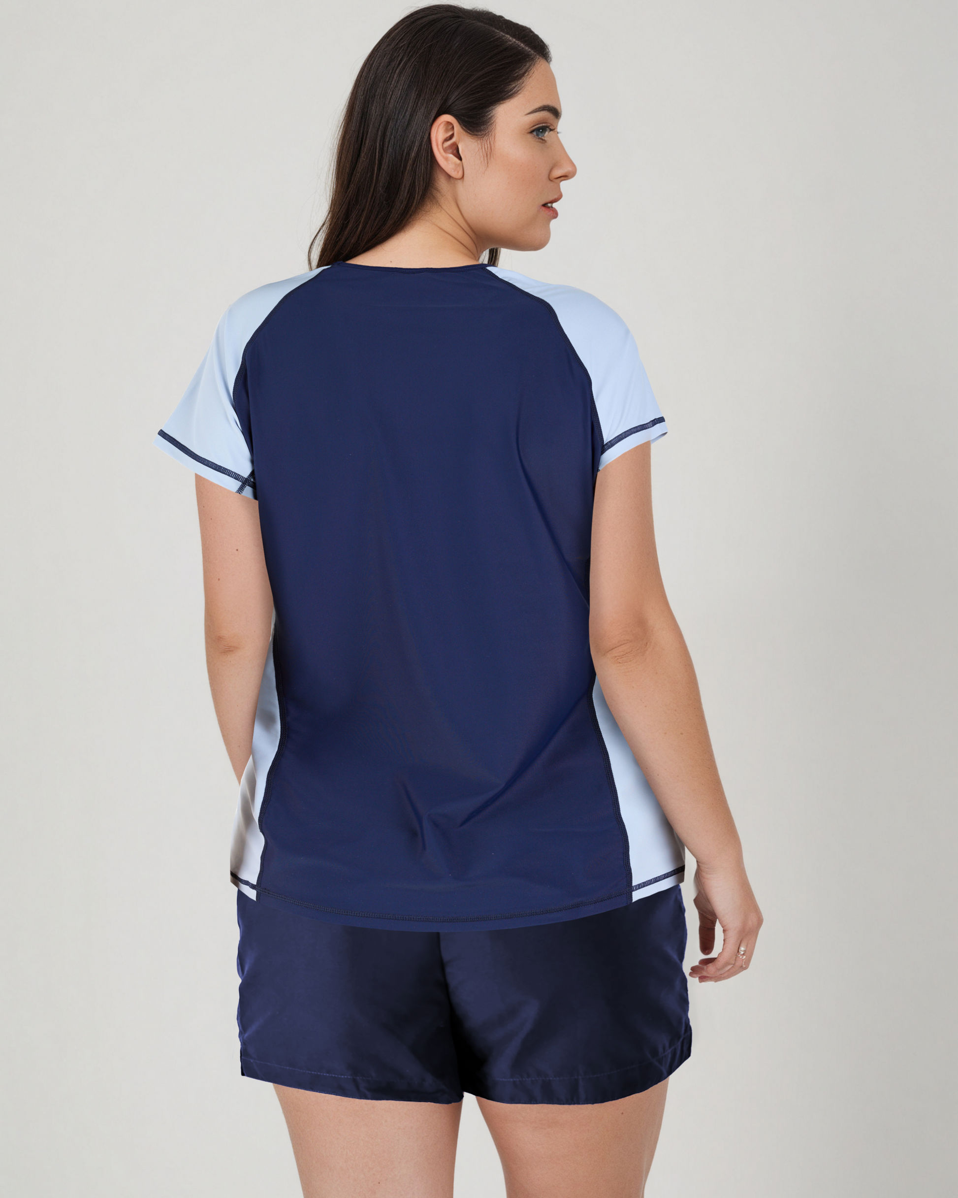 Woman wearing a navy and light blue sports outfit on a plain background
