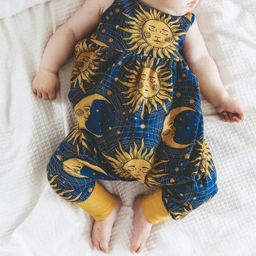boho baby romper handmade in the uk by Lottie & Lysh. Featuring a navy background with bohemian themed gold stars, sunshines and moons with mustard ankle cuffs.