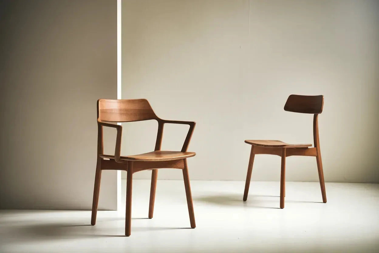 Two wooden chairs with minimalist design against a neutral backdrop.
