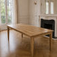 Wooden table in a room with large windows and a fireplace.