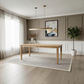 A modern minimalist dining room featuring a light oak rectangular wooden dining table on a textured light gray rug, set against a warm taupe paneled wall with a gold linear pendant light and a potted green plant.