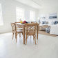A light natural wood dining table with four matching wooden chairs in a bright, modern dining room with white shiplap walls and light wood floors.