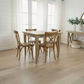 A light oak dining table with four matching wooden chairs in a bright, modern dining room with white shiplap walls and light wood floors.