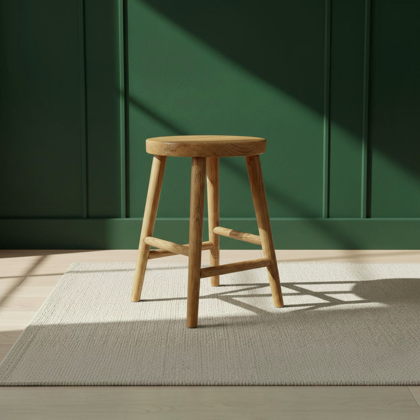 A round wooden stool with four legs and crossed front support bars, shown on a light rug against a dark green paneled wall with sunlight casting shadows.