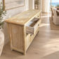 A light natural wood sideboard cabinet with a distressed finish, featuring a top with a herringbone pattern, two open drawers with one pulled out, and two lower cabinet doors. It is shown in a bright, modern room with light wood floors and a view of the ocean in the background.
