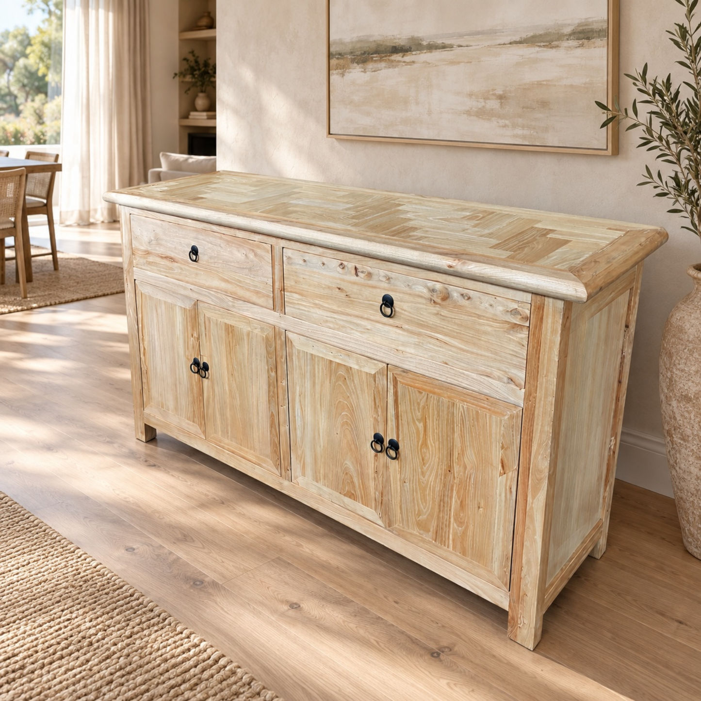 A light natural wood sideboard cabinet with two drawers and three doors, styled in a bright, modern living room with wood floors and neutral decor.