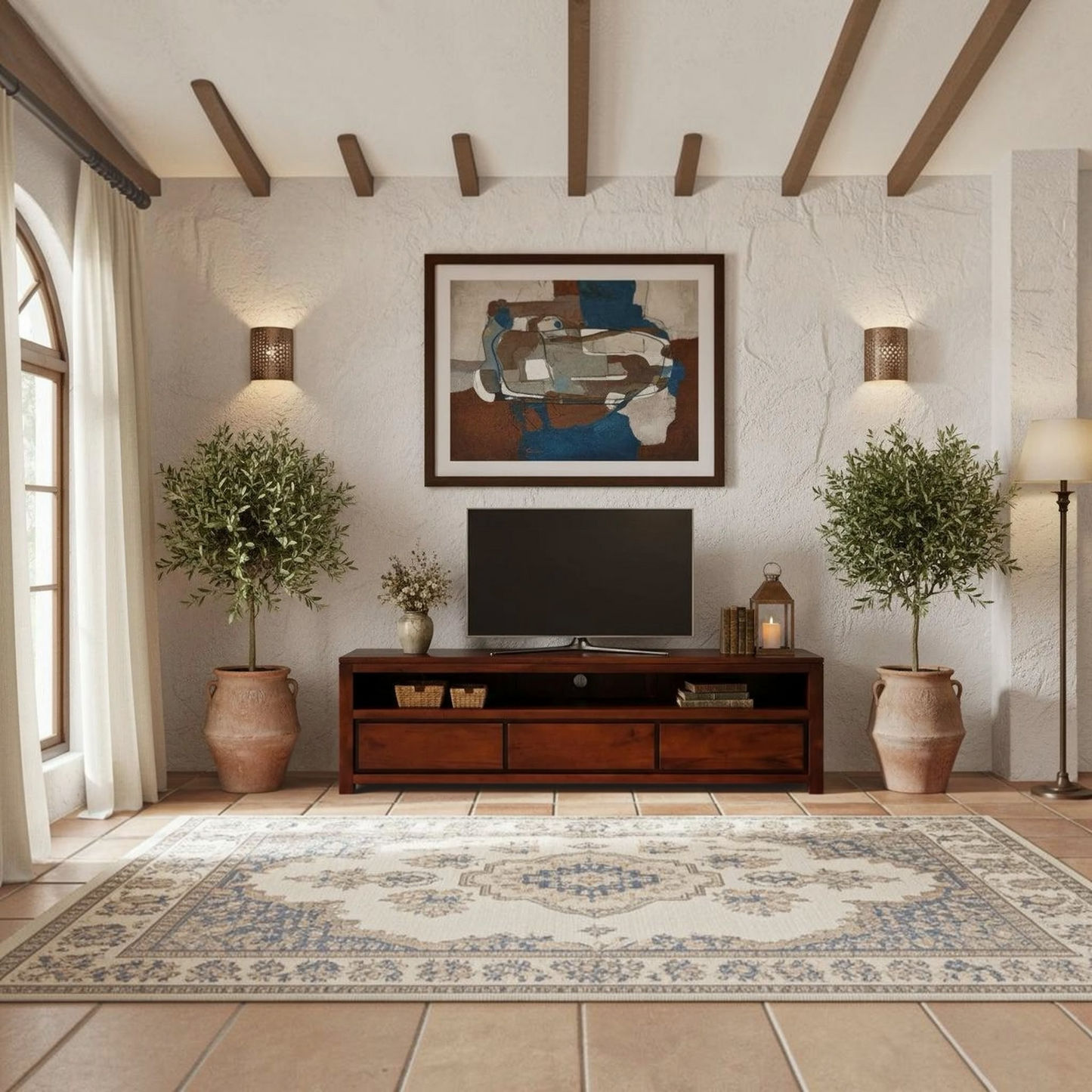 A styled living room interior featuring a dark wood media console with a television, a large framed abstract painting on the textured wall, two potted olive trees, a patterned area rug, and warm ambient lighting.