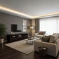 A modern living room interior with a light beige sofa, matching armchair, dark wood media console, white coffee table, textured beige rug, dark wood flooring, and a gray accent wall with framed art and a TV.
