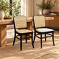 Two dining chairs in a warm, sunlit room. One chair has a black frame with a woven cane backrest and seat, and the other has a black frame with a light gray upholstered seat and cane backrest.