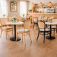 Café interior with wooden tables and chairs, light-colored walls, and a counter.