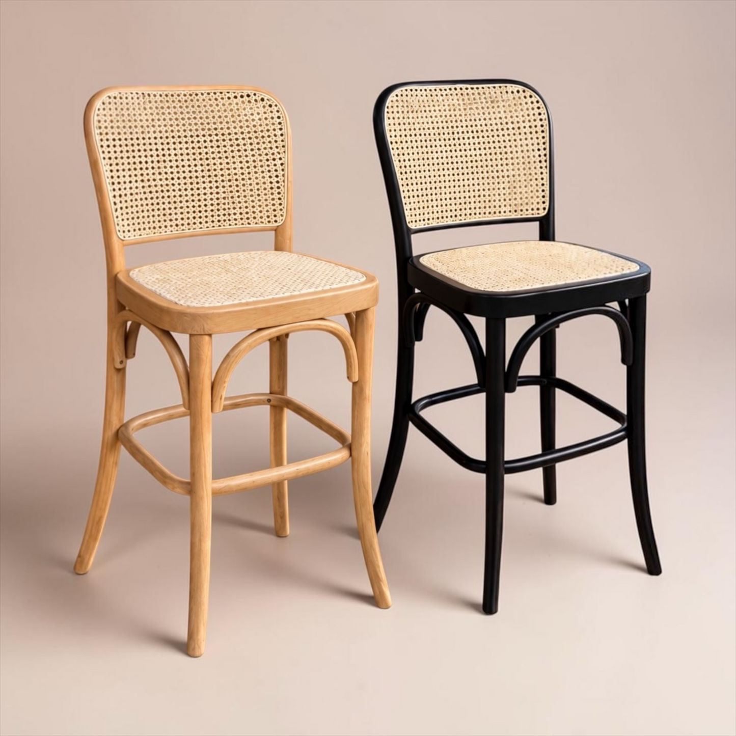 Two bentwood bar stools with woven cane seats and backs, shown side by side on a warm beige studio background. One stool has a light natural wood frame, and the other has a black frame.