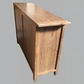 A rustic wooden sideboard or console table with a natural light brown finish, shown from a three-quarters perspective against a solid gray background.