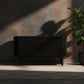 Dark radiator against a textured wall with a plant to the right