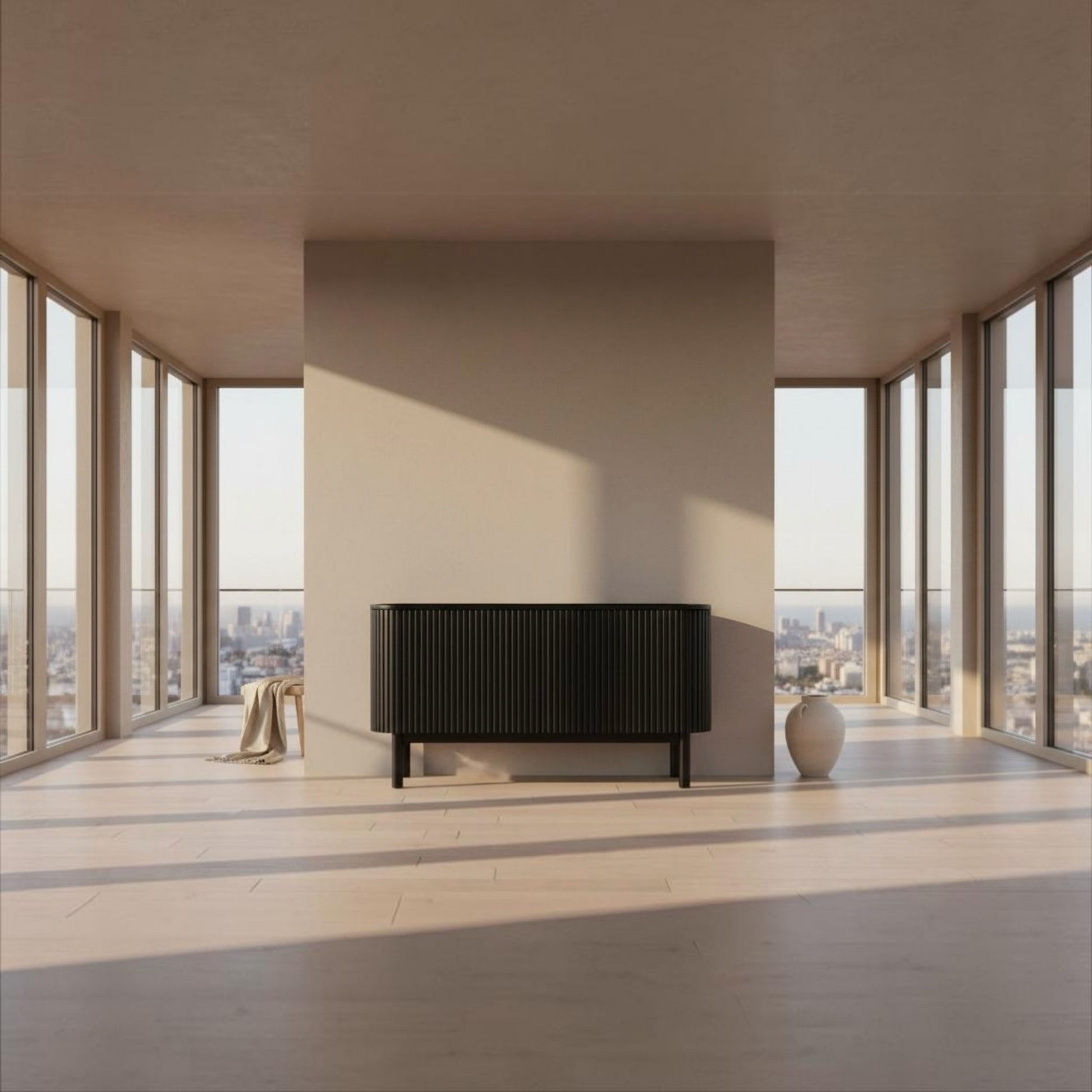 A modern black ribbed sideboard cabinet with slim legs, positioned in a minimalist, sunlit room with high windows and a beige wall behind it.