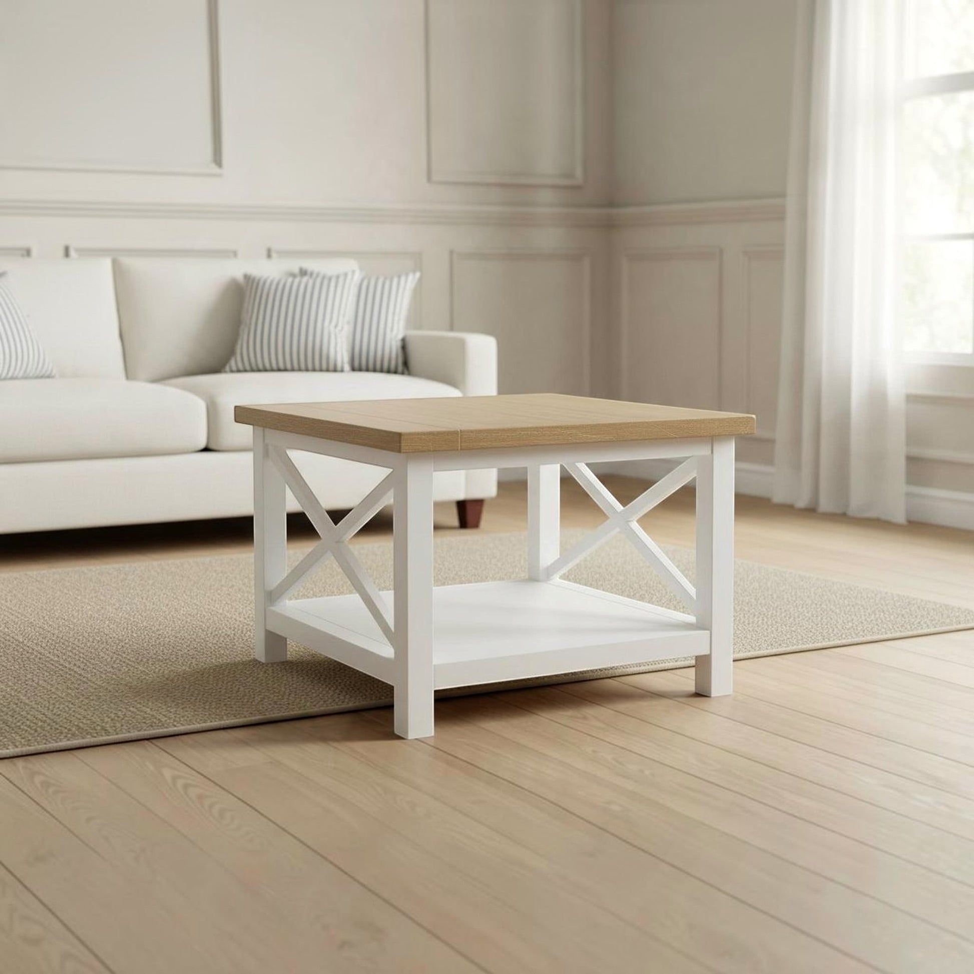 A white wooden coffee table with a light natural wood top and a lower shelf, styled in a bright, modern living room with a white sofa and light wood floors.