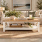 A white and light wood coffee table with a lower shelf, styled in a bright, modern living room with a beige sofa, plants, and a woven rug.