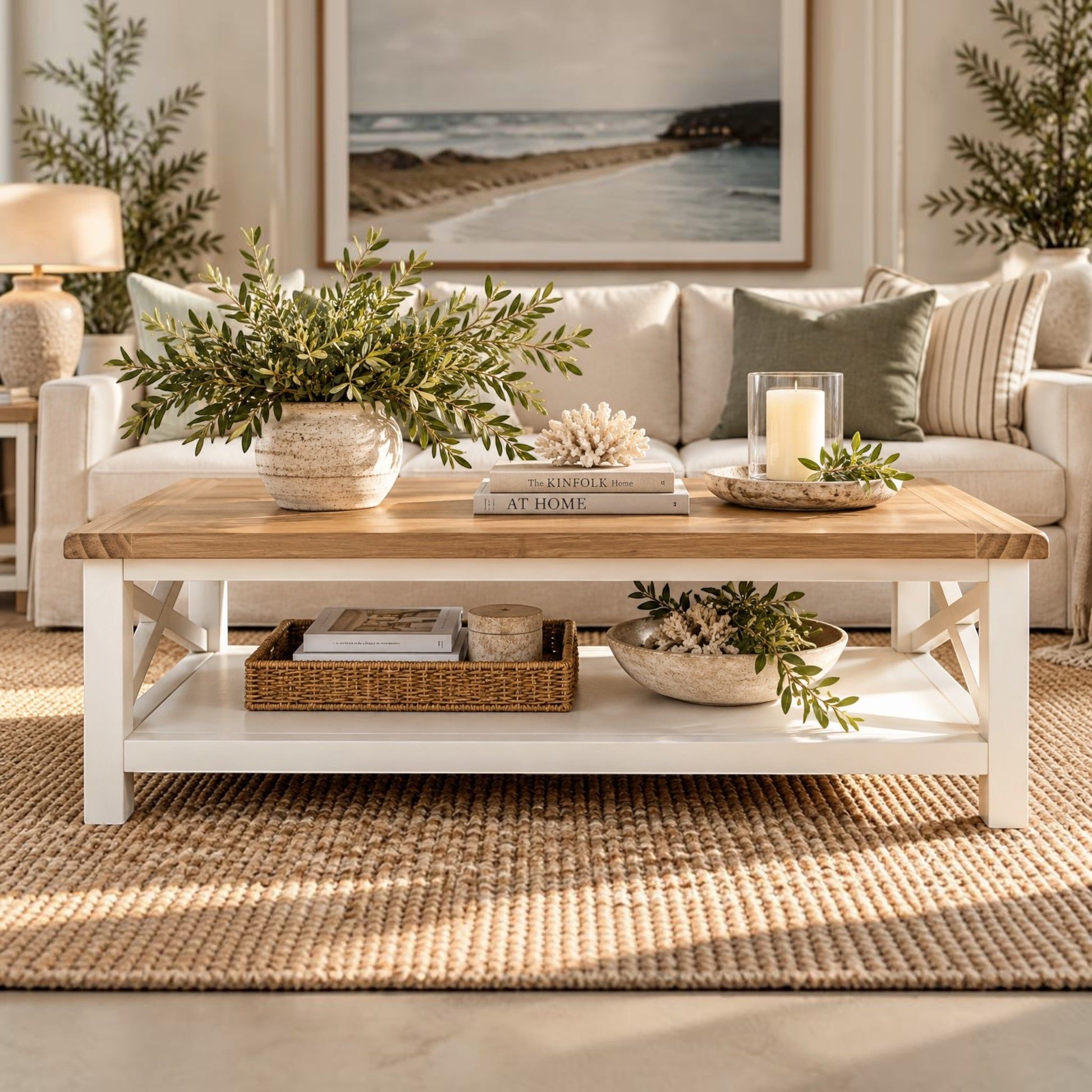 A white and light wood coffee table with a lower shelf, styled in a bright, modern living room with a beige sofa, plants, and a woven rug.