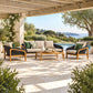 Outdoor patio furniture set under a wooden pergola beside a pool, featuring a beige and black woven sofa, two matching armchairs with green accent pillows, and a wooden coffee table on a stone patio.