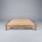 A minimalist wooden platform bed frame with light natural wood slats, photographed against a neutral gray studio background.