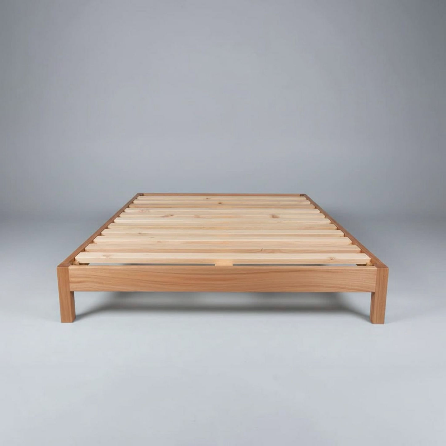 A minimalist wooden platform bed frame with light natural wood slats, photographed against a neutral gray studio background.