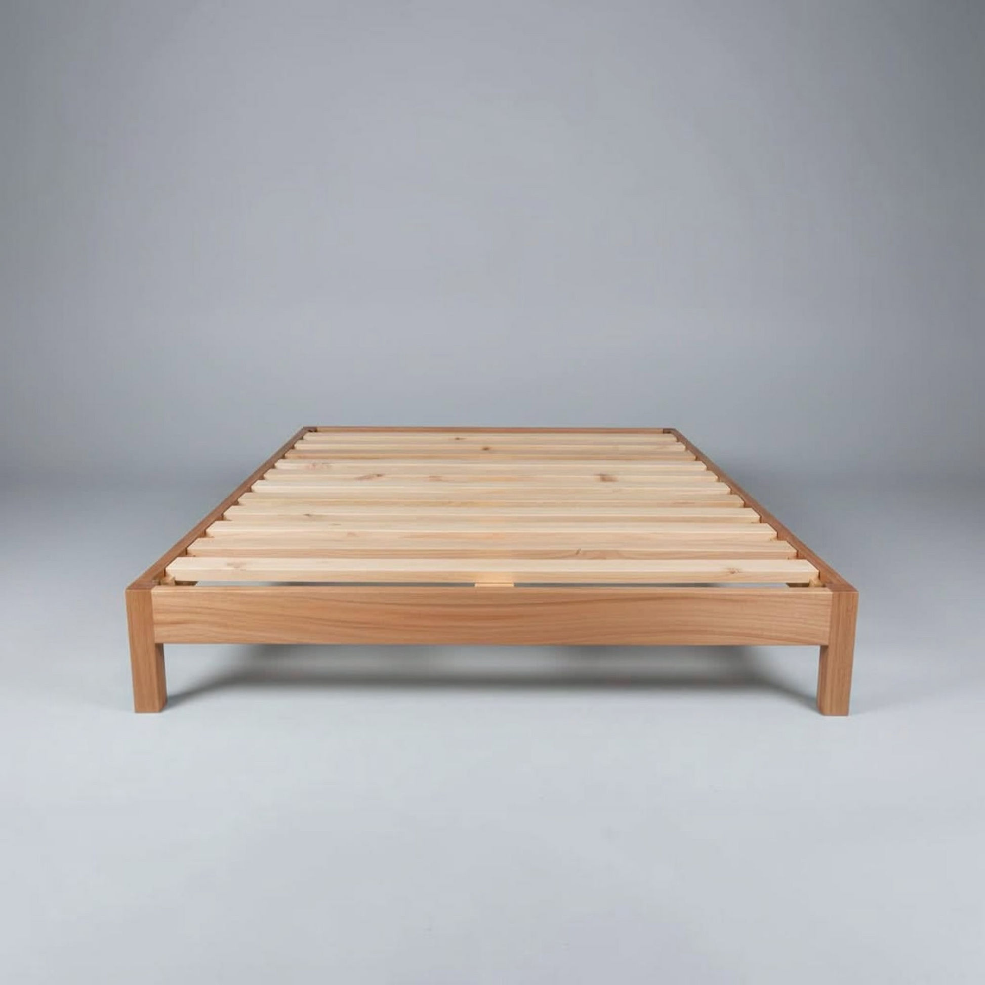 A minimalist wooden platform bed frame with light natural wood slats, photographed against a neutral gray studio background.