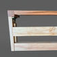 Close-up of a wooden shelf or bracket with two-tone natural wood construction, including a darker brown top rail and a lighter beige wood frame, shown against a solid gray background.