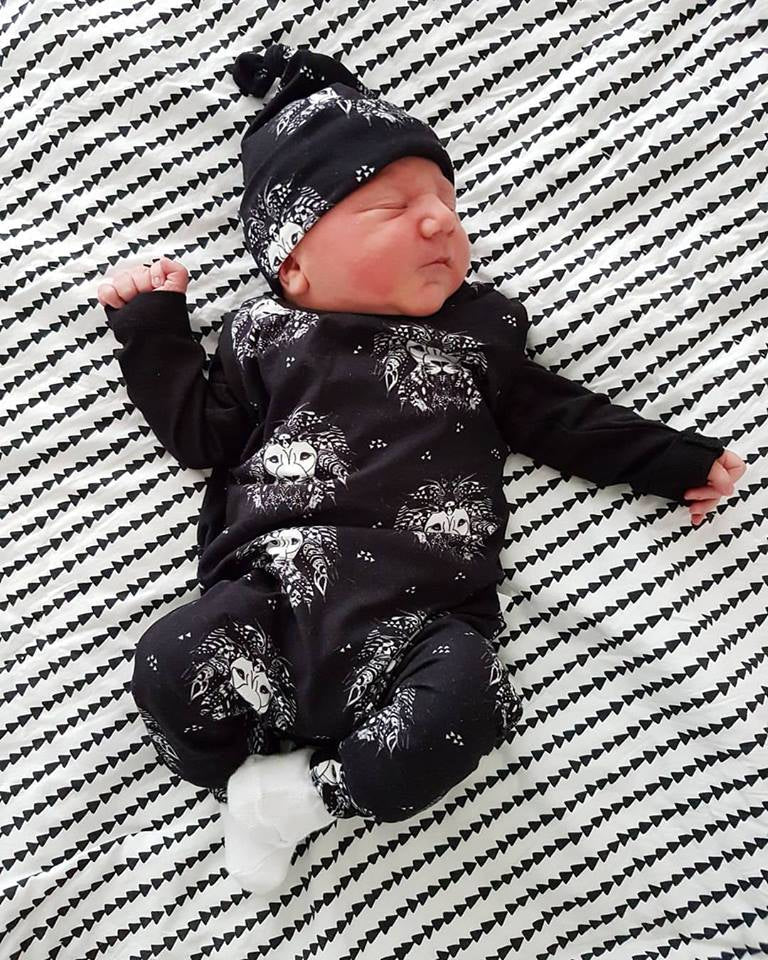 New born baby boy wearing black lion print outfit with matching hat