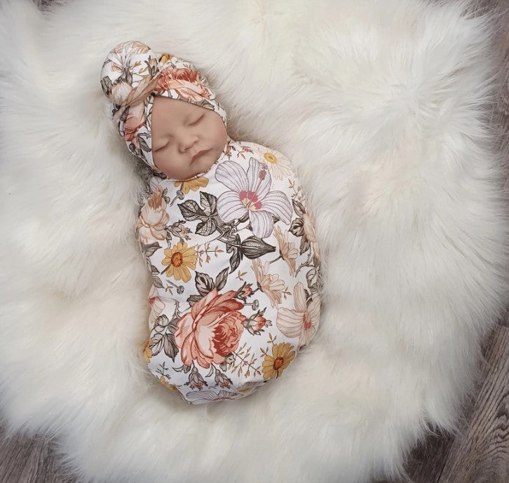newbonr baby girl wrapped in a Lottie & Lysh floral rose pirnt swaddle with matching turban style hat