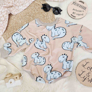beige sweater romper for babies and toddlers featuring a cute blue dinosaur motif
