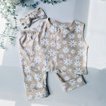 Flat lay image of a girls jersey co-ordinates set of trousers and waistcoat in beige, with white daisy style flowers