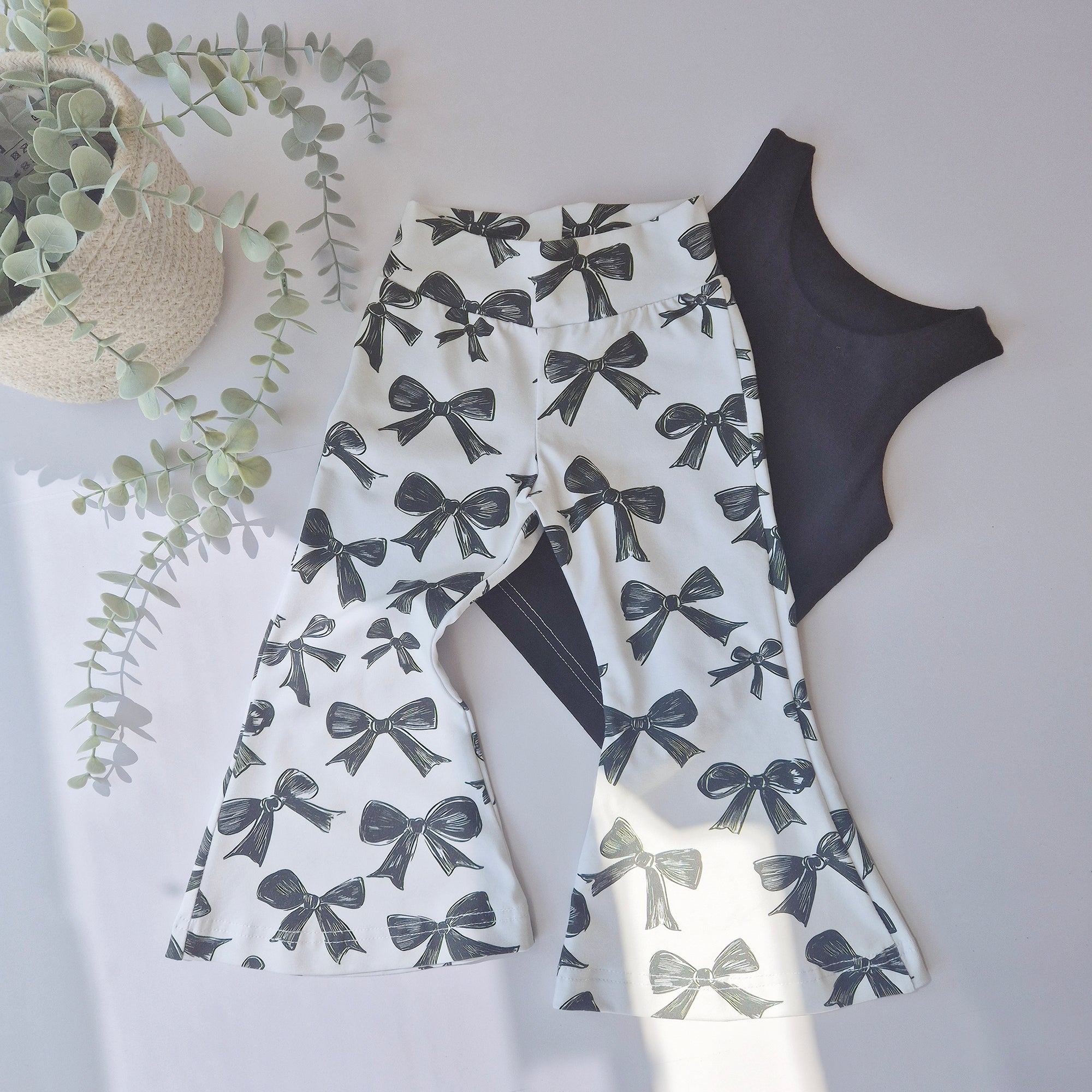flared bow print trousers by Lottie & Lysh. Flat lay image with a black vest top.