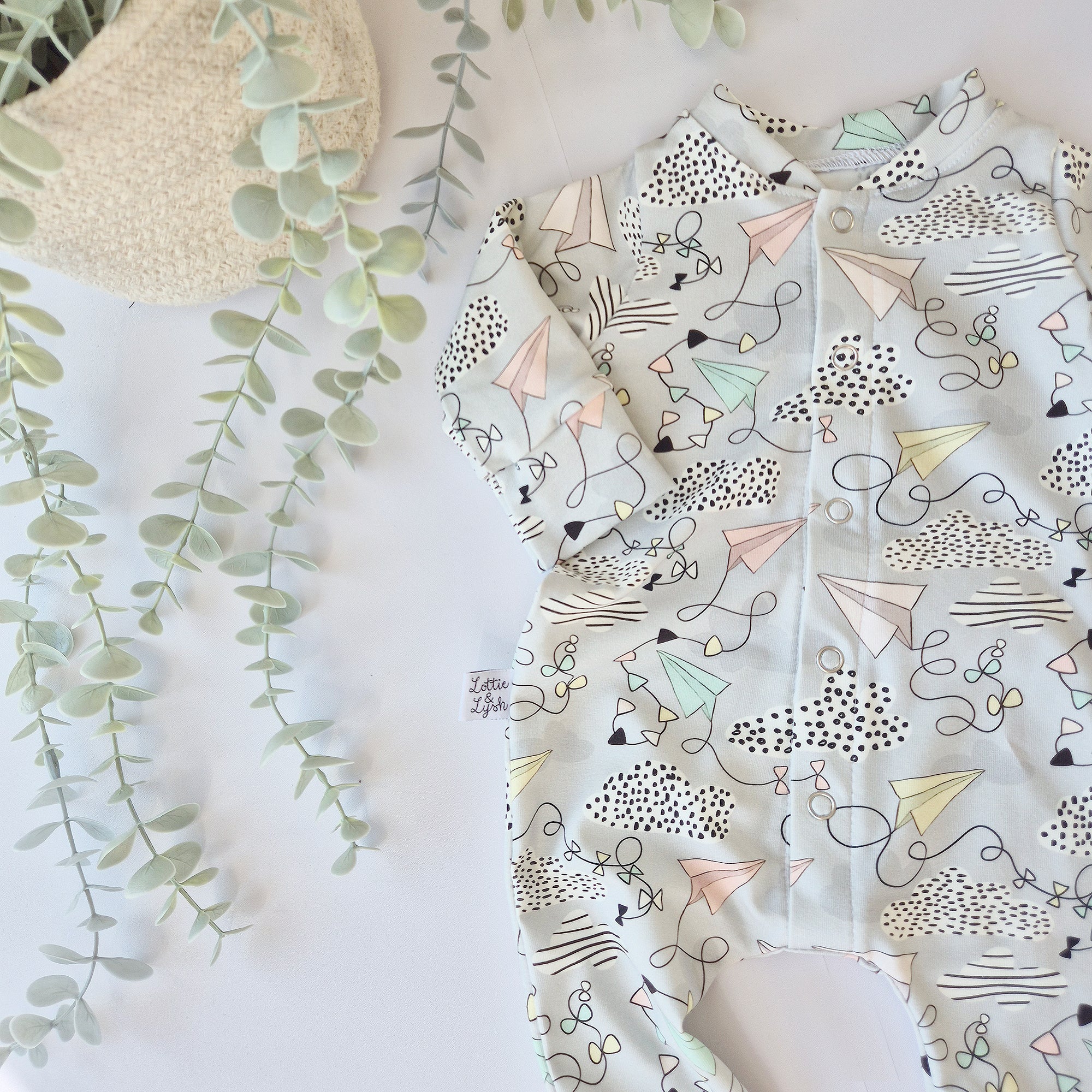 Baby romper with geometric plane and kite pattern on a light background