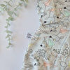Fabric with abstract patterns on a light background, featuring a brand tag.