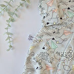 Fabric with abstract patterns on a light background, featuring a brand tag.