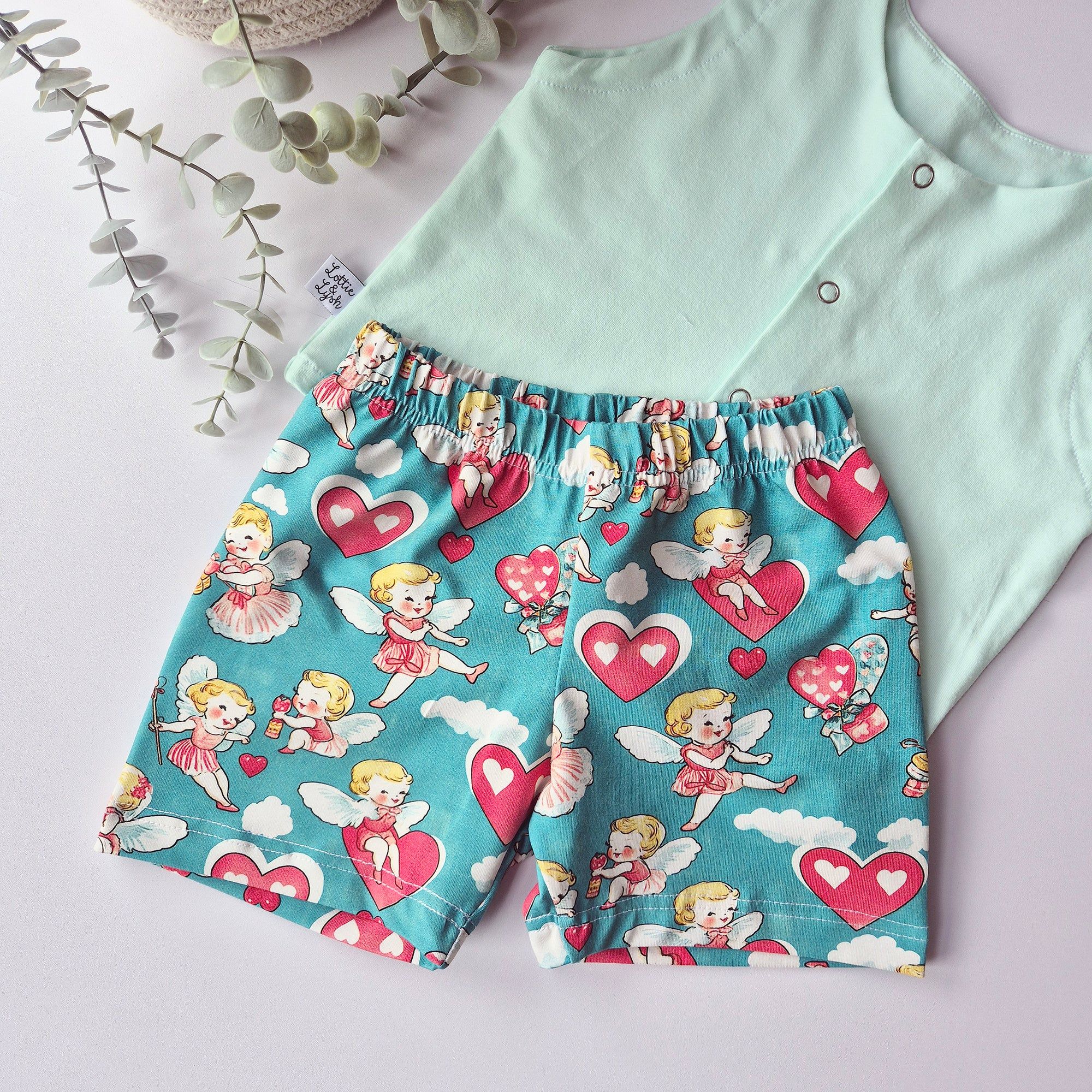 Children's shorts with cherubs and heart pattern on a light green shirt