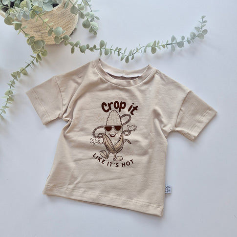 Beige t-shirt with a graphic design on a light background - crop it like its hot