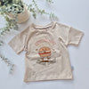 Beige t-shirt with a cartoon burger design and text on a light background