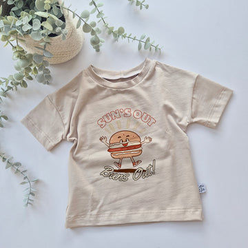 Beige t-shirt with a cartoon burger design and text on a light background