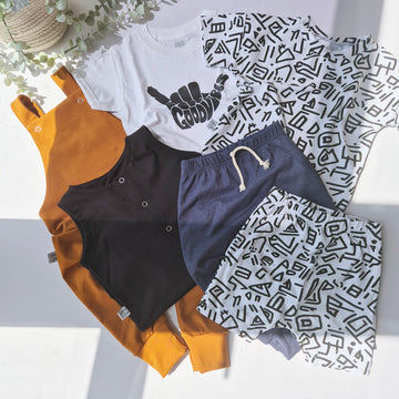 Collection of casual clothing items including a white t-shirt, shorts, and pants with geometric patterns on a light background.